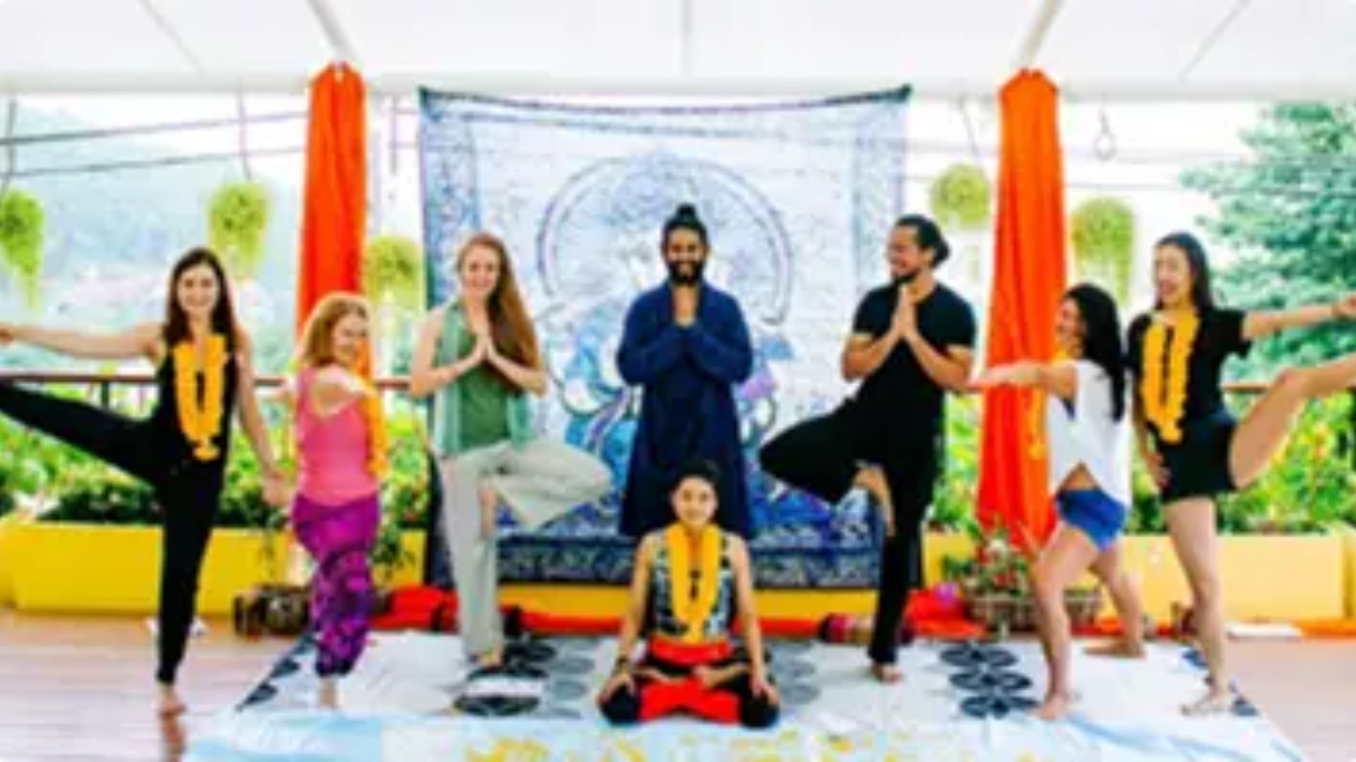 Aerial yoga class with orange hammocks and students in poses