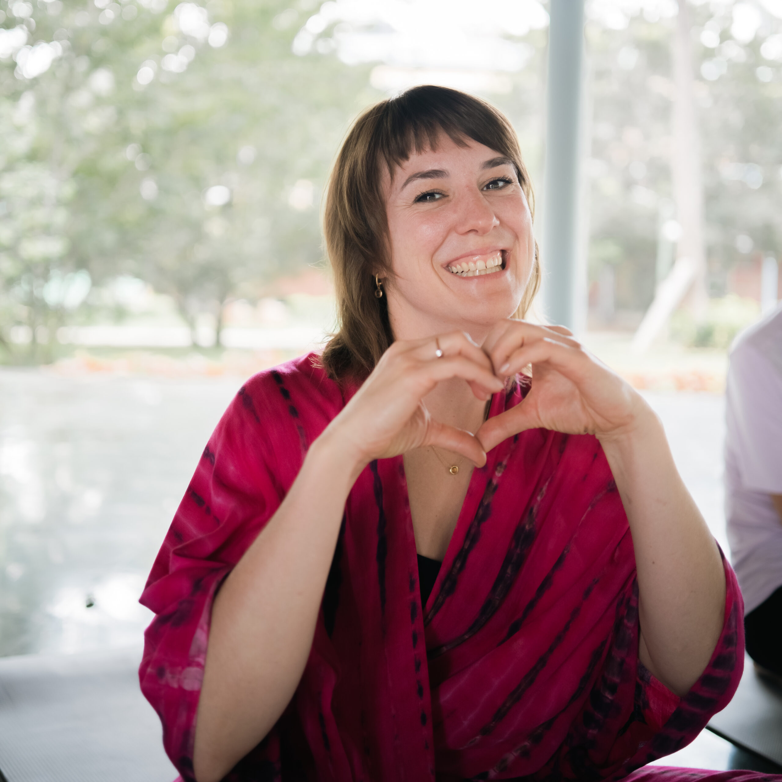 Yoga Nisarga student in a pink shawl making a heart shape with her hands