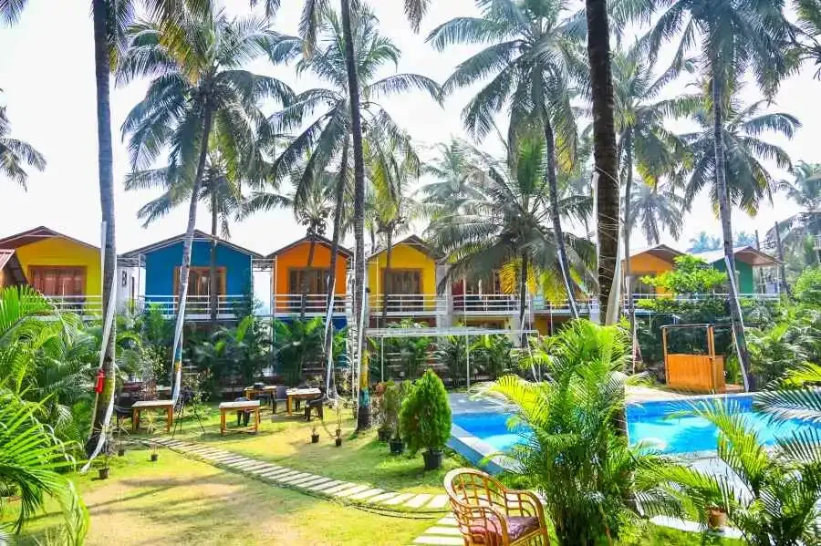 Garden, swimming pool and cottages at the yoga retreat in Goa
