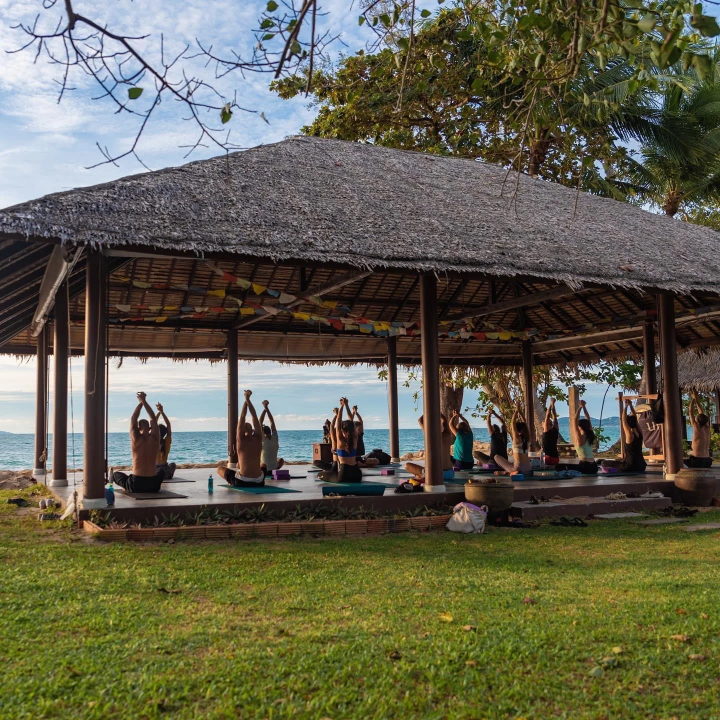 Students practising together in an open-sided sala looking out to the sea.