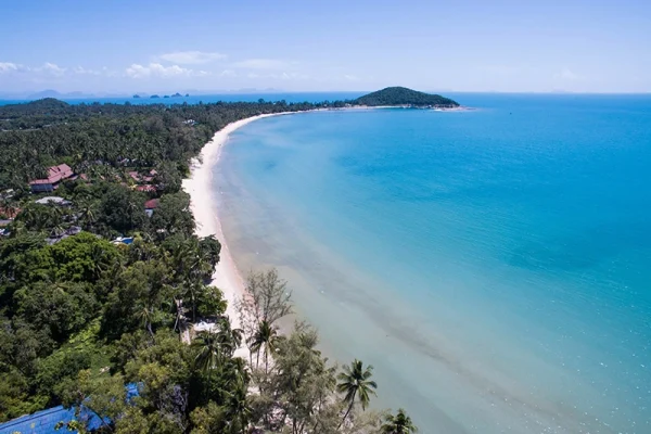 Aerial view of the Koh Samui coastline near this yoga retreat thailand property, turquoise sea and palm trees.