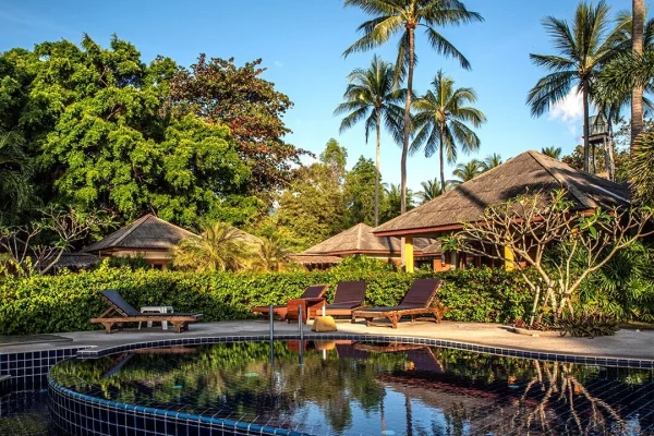 Round plunge pool at the yoga retreat thailand property in Lipa Noi, framed by palm trees and bungalows.
